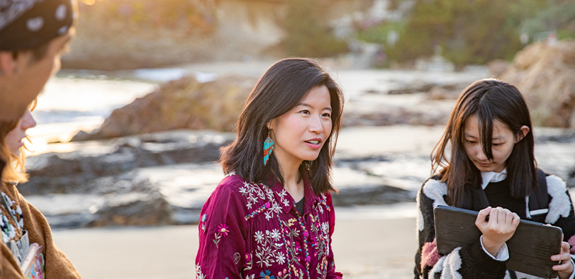 A photo of an instructor giving a lecture on the beach.