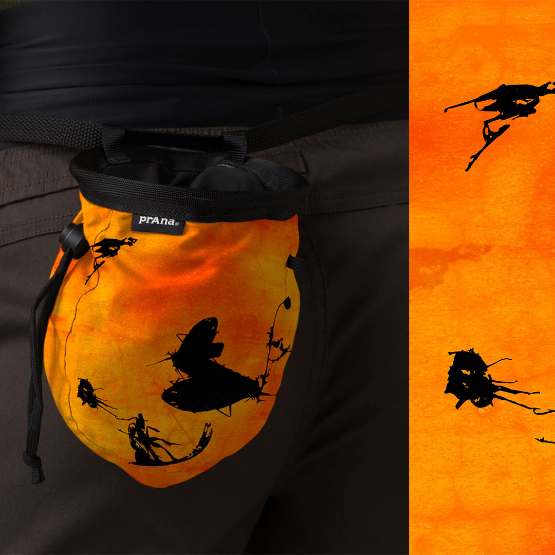 A photo of an orange drawstring bag with a black scribble graphic on it.