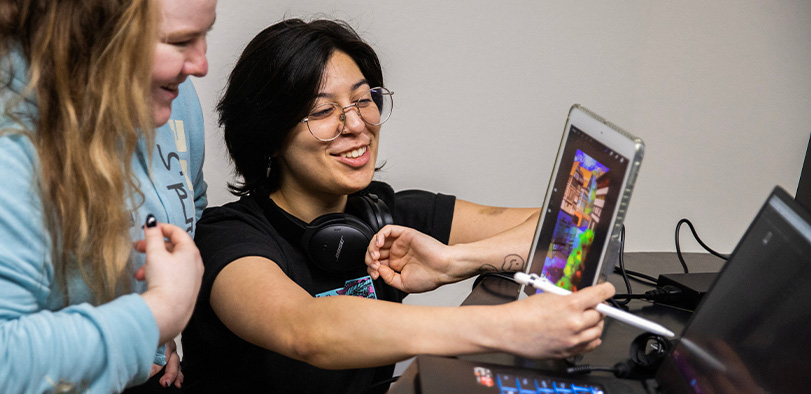 A photo of students working together on a tablet.