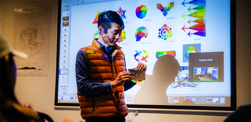 A photo of an instructor showing colorful projections.