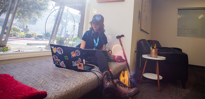 A photo of a student looking at their laptop in the library.