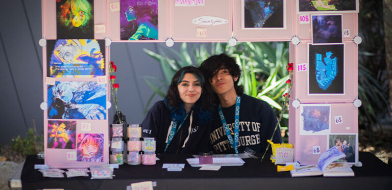 A photo of two sttudents at an art market booth.