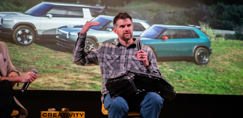 A photo of Brian Gase presenting at the Rivian Theater.