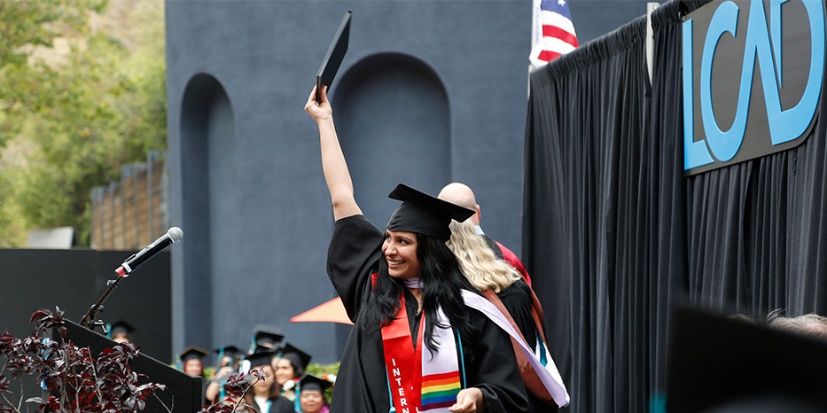 A photo of a student walking across the graduation stage in a cap and gown.